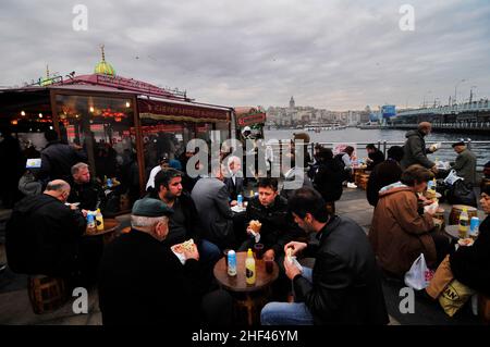 Pesce sgombro alla griglia per i famosi sandwich di pesce serviti da barche colorate presso il ponte Galata di Istanbul, Turchia. Foto Stock