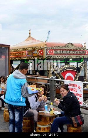 Pesce sgombro alla griglia per i famosi sandwich di pesce serviti da barche colorate presso il ponte Galata di Istanbul, Turchia. Foto Stock