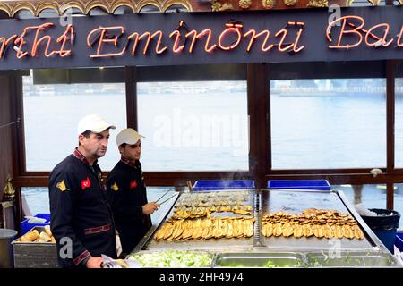 Pesce sgombro alla griglia per i famosi sandwich di pesce serviti da barche colorate presso il ponte Galata di Istanbul, Turchia. Foto Stock