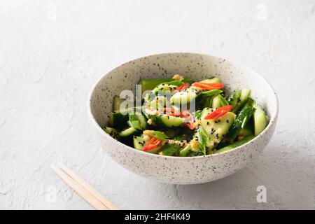 Insalata speziata asiatica Cetrioli spezzati con coriandolo fresco, zenzero, peperoncino, aceto nero su sfondo bianco. Famoso antipasto cinese freddo. Clos Foto Stock