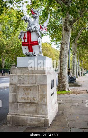 Una statua del drago con lo scudo trasversale di St Georges che segna il confine per la città di Londra lungo il lungofiume del Tamigi sotto il treeline di Londra Foto Stock