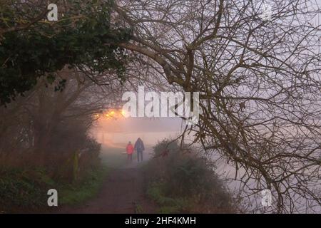 Wareham, Dorset Regno Unito. 14th gennaio 2022. Tempo britannico: Un freddo inizio a Wareham, Dorset come nebbia appende sopra il fiume Frome al mattino. Una coppia fa una passeggiata lungo il fiume. Credit: Carolyn Jenkins/Alamy Live News Foto Stock