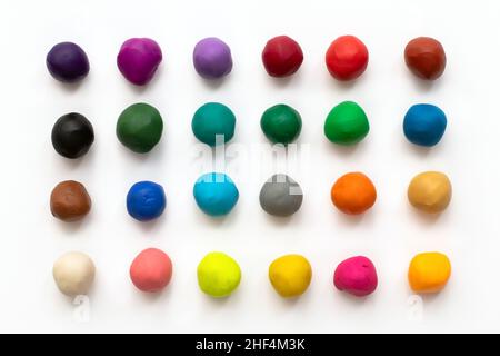 Pezzi o palle di argilla modellante plastilina colorata isolati su sfondo bianco. Vista dall'alto con ombra. Creatività bambini concetto giocattoli. 24 colori Foto Stock