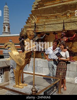 Thailandia. Bangkok. Coppia turistica ammirando la statua dorata al Grand Palace. Foto Stock