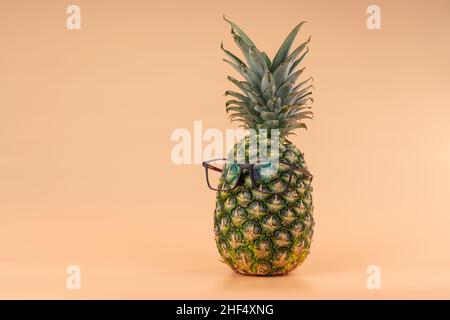 Interpretazione della frutta di ananas in un'immagine umana come in medicina oftalmica con i vetri su sfondo giallo. Spazio di copia Foto Stock