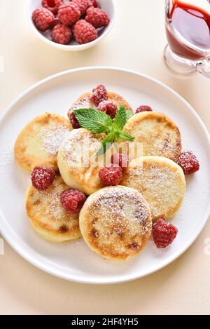 Pancake al formaggio casolare con lamponi freschi sul piatto su sfondo di pietra chiaro. Vista ravvicinata Foto Stock