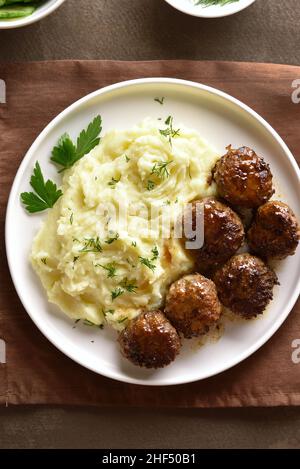 Carni macinate cotolette con purè di patate su piastra bianca su sfondo marrone. Vista superiore, laici piatta Foto Stock