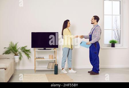 Felice giovane donna servizio clienti cliente grata scuote le mani con uomo tecnico. Foto Stock