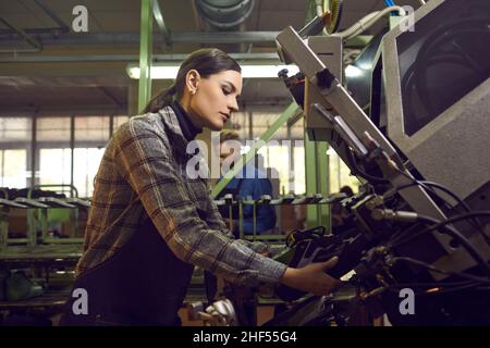 Donna che utilizza uno speciale sistema di stampa industriale mentre fa nuove sneakers alla fabbrica di scarpe Foto Stock