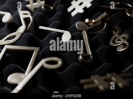 Un concetto che mostra una sezione di schiuma sonora grigia con simboli di musica d'oro e note sparse sopra di essa - 3D rendering Foto Stock