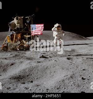L'astronauta John W. Young, comandante della missione di atterraggio lunare Apollo 16, salta dalla superficie lunare mentre saluta la bandiera degli Stati Uniti. Foto Stock