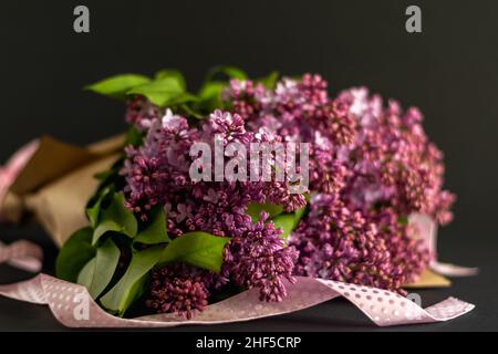 Bel bouquet di fiori di lilla con nastri su sfondo scuro. Foto orizzontale. Foto Stock