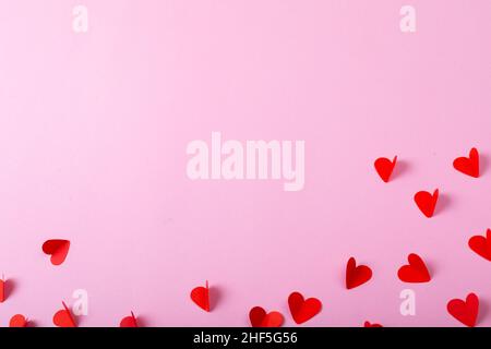 Vista dall'alto di tagli di carta a forma di cuore rosso sparsi su sfondo lavanda con spazio di copia Foto Stock