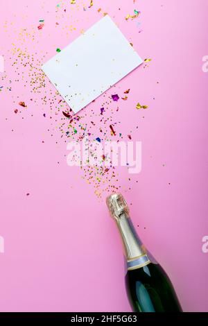 Vista dall'alto della bottiglia di champagne con confetti sparsi con spazio per la copia su carta bianca Foto Stock