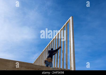 Un carpentiere per chiodare travi di legno con un martello pneumatico Foto Stock