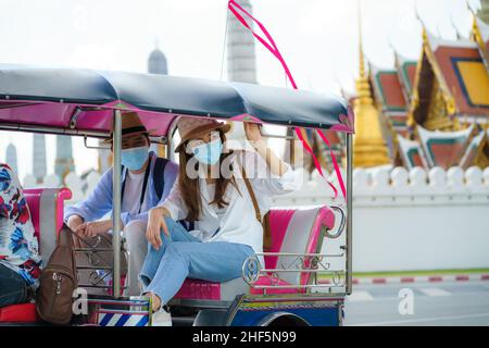 I turisti asiatici coppia tuk tuk passeggero tassista nativo di viaggio vicino Wat phra keaw a Bangkok, Thailandia Foto Stock