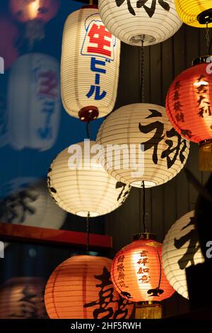 Molte tradizionali lanterne colorate di carta illuminata appese al soffitto nel ristorante asiatico Foto Stock