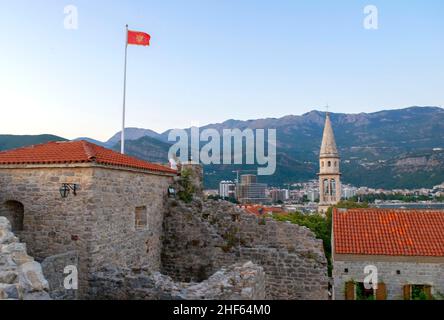 Montenegro - Budva: 8 settembre 2021: Bandiera del Montenegro sullo sfondo della città di Budva e delle montagne. La bandiera del Montenegro sorvola la città vecchia Foto Stock