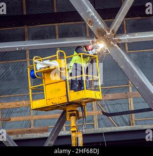 Saldatore impegnato a unire un pezzo di metallo, indossando un dispositivo di protezione Foto Stock