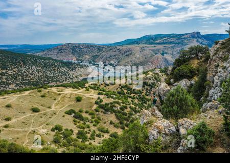 Turista maschile in piedi sulla scogliera di roccia e godere di una splendida vista della baia di Balaklava a Sevastopol, Crimea. Foto Stock
