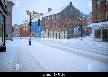 Water Street a George Street nel centro di St. John's. le strade sono coperte di neve fresca e bianca. La fabbrica di birra Yellowbelly è un edificio in mattoni. Foto Stock