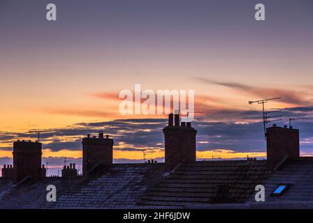 Tegole coperte di gelo e camini e alba in una scena urbana Foto Stock