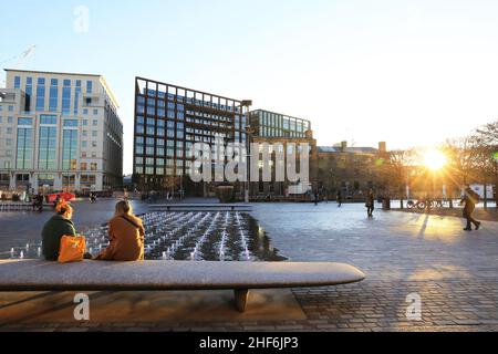 Sole invernale su una tranquilla Granary Square sotto le regole del Plan B Covid, con gli uffici blocchi di merci via oltre, a Kings Cross, nel nord di Londra, Regno Unito Foto Stock