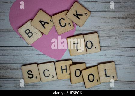 Concetto di ritorno a scuola. Torna a scuola scritto su lettere scrabble su un rustico sfondo di legno. Preparazione per tornare a scuola dopo la s. Foto Stock