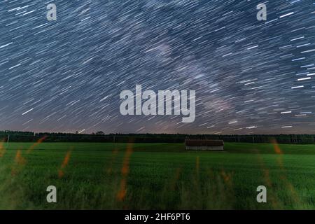 Startrails su una piccola capanna in un terreno agricolo nella notte stellata, bella natura e concetto di moto della terra Foto Stock