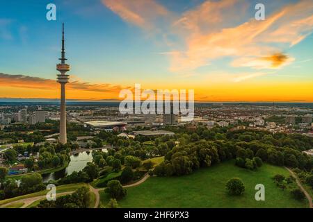 L'alba estiva si staglia sulla splendida città bavarese di Monaco con la sua popolare e spettacolare vista panoramica sul parco olimpico con l'alta torre sotto il cielo di colore arancione al mattino Foto Stock