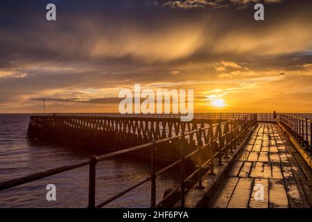 Una gloriosa mattinata alla spiaggia di Blyth, con una splendida alba sul vecchio molo di legno che si estende fino al Mare del Nord Foto Stock