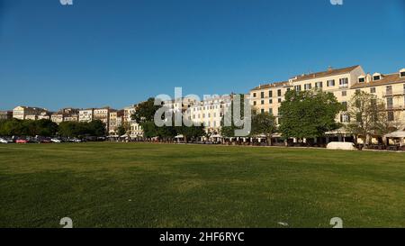 Grecia, Isole greche, Isole IONIE, Corfù, Corfù, Centro storico, piazza di fronte al Liston, prato verde, case di Liston dietro la piazza, cielo blu, senza nuvole Foto Stock