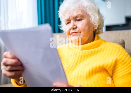 le mani anziane della donna hanno stropicciato la pelle in primo piano sulle ginocchia. Foto Stock