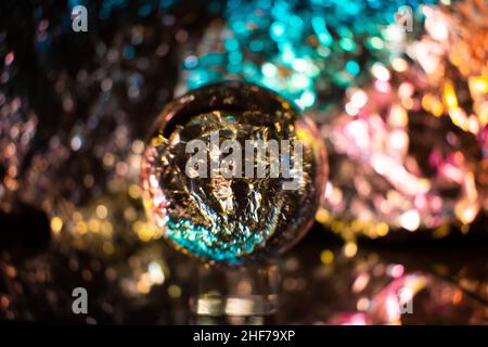 Fotografia del globo della neve lente trasparente della sfera di cristallo su uno sfondo sfocato, molto artistico, futuristico, colorato, vibrante. Fondo e retro cool Foto Stock