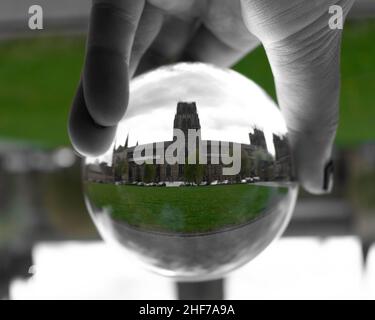 Cattedrale di Durham Inghilterra nord-orientale, Regno Unito (UK). Fotografa attraverso una sfera di cristallo di vetro con spruzzi di colore verde che danno un effetto globo di neve. Foto Stock