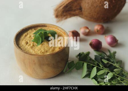 Chutney di cocco. Condimento piccante a base di noci di cocco fresche, peperoncini rossi e scalogni. Servito in una ciotola di legno. Un accompagnamento per una torta croccante in padella. Scatto Foto Stock