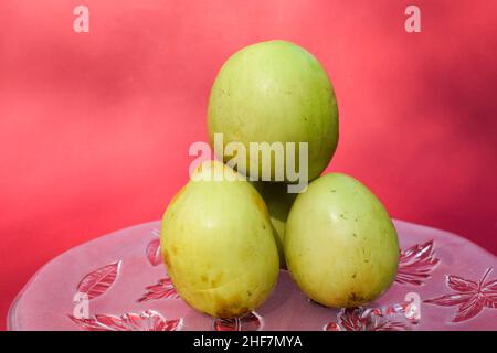 Frutta indiana fresca e biologica chiamata Jujube verde o jujube mela o mela Ber. Verde indiano jujuba prugna bora su sfondo rosso Foto Stock