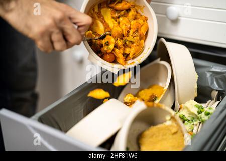 Gettando via cibo residuo nel cestino o nel cestino della spazzatura Foto Stock