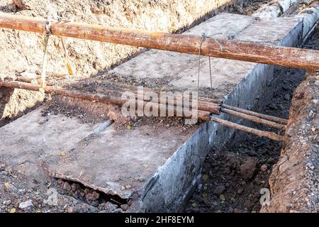 Sostituzione dei tubi di riscaldamento e ammodernamento dell'impianto di riscaldamento. Lavori di costruzione su grandi tubi di ferro ad una profondità di trincea scavata Foto Stock