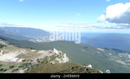 Breathtaking landscape of green forested mountains on blue cloudy sky background. Aerial of amazing green hills covered by trees. Foto Stock