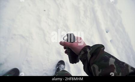 Il soldato tiene in mano una granata di allenamento mentre passa esercizi militari nell'esercito, neve sfondo. Un soldato in mimetizzazione che tiene una frag Foto Stock