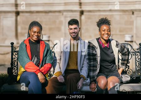 Ritratto di tre persone di diverse etnie seduti su una panchina all'aperto Foto Stock