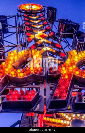 Luci colorate decorano un giro del parco di divertimento contro un cielo crepuscolo a Costa Mesa, CA. Foto Stock