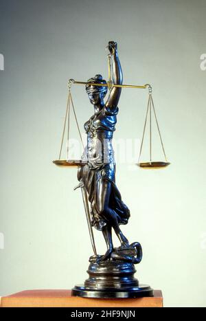Una statua simbolica in bronzo di una giustizia femminile cieca che porta una spada e tiene le bilance della giustizia. Foto Stock