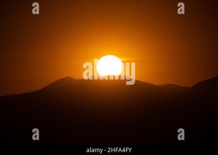 Santiago, Metropolitana, Cile. 14th Jan 2022. Il sole si nasconde dietro una delle colline che circondano Santiago, Cile. (Credit Image: © Matias Basualdo/ZUMA Press Wire) Credit: ZUMA Press, Inc./Alamy Live News Foto Stock