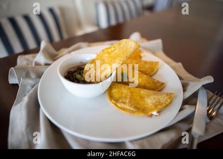 Piatto con quesadilla tradizionale e tazza di fagioli su tovagliolo grigio Foto Stock