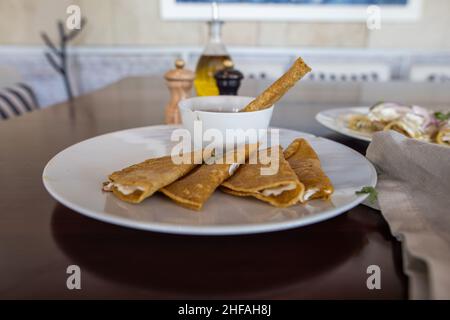 Piatto con quesadilla tradizionale e tazza di fagioli su tavola marrone Foto Stock