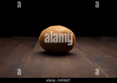 immagine naturale di un kiwi biologico da vicino su una superficie rustica in legno e sfondo nero Foto Stock