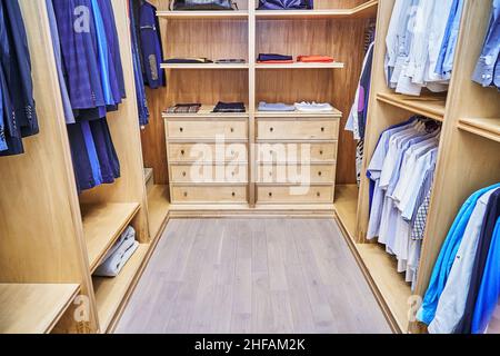 Elegante passeggiata in armadio con mobili in legno massello di acero e impiallacciatura per lo stoccaggio di vestiti con corona di stampaggio in appartamento Foto Stock