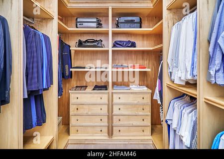 Elegante passeggiata in armadio con mobili in legno massello di acero e impiallacciatura per lo stoccaggio di vestiti con corona di stampaggio in appartamento Foto Stock